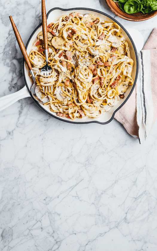 Spaghetti carbonara recipe dish in a pan on a marble surface