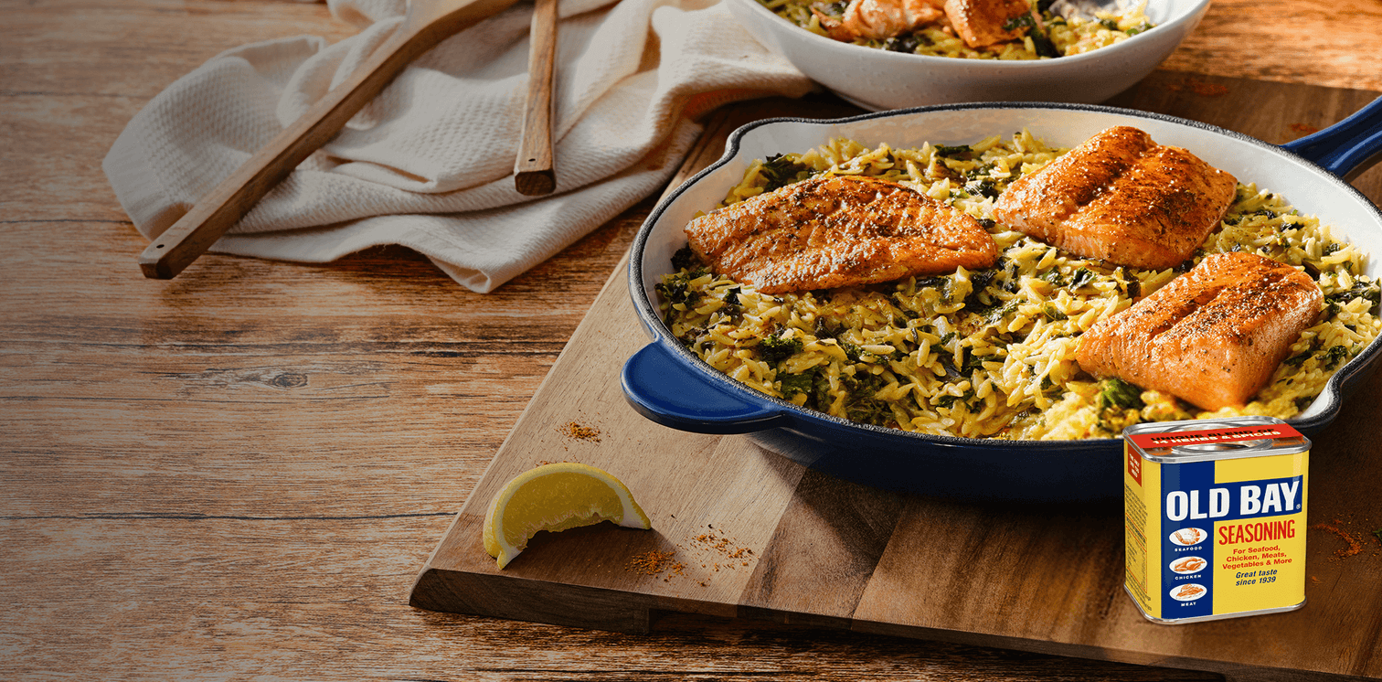 Salmon dish with rice and greens on a wooden table, featuring Old Bay seasoning.