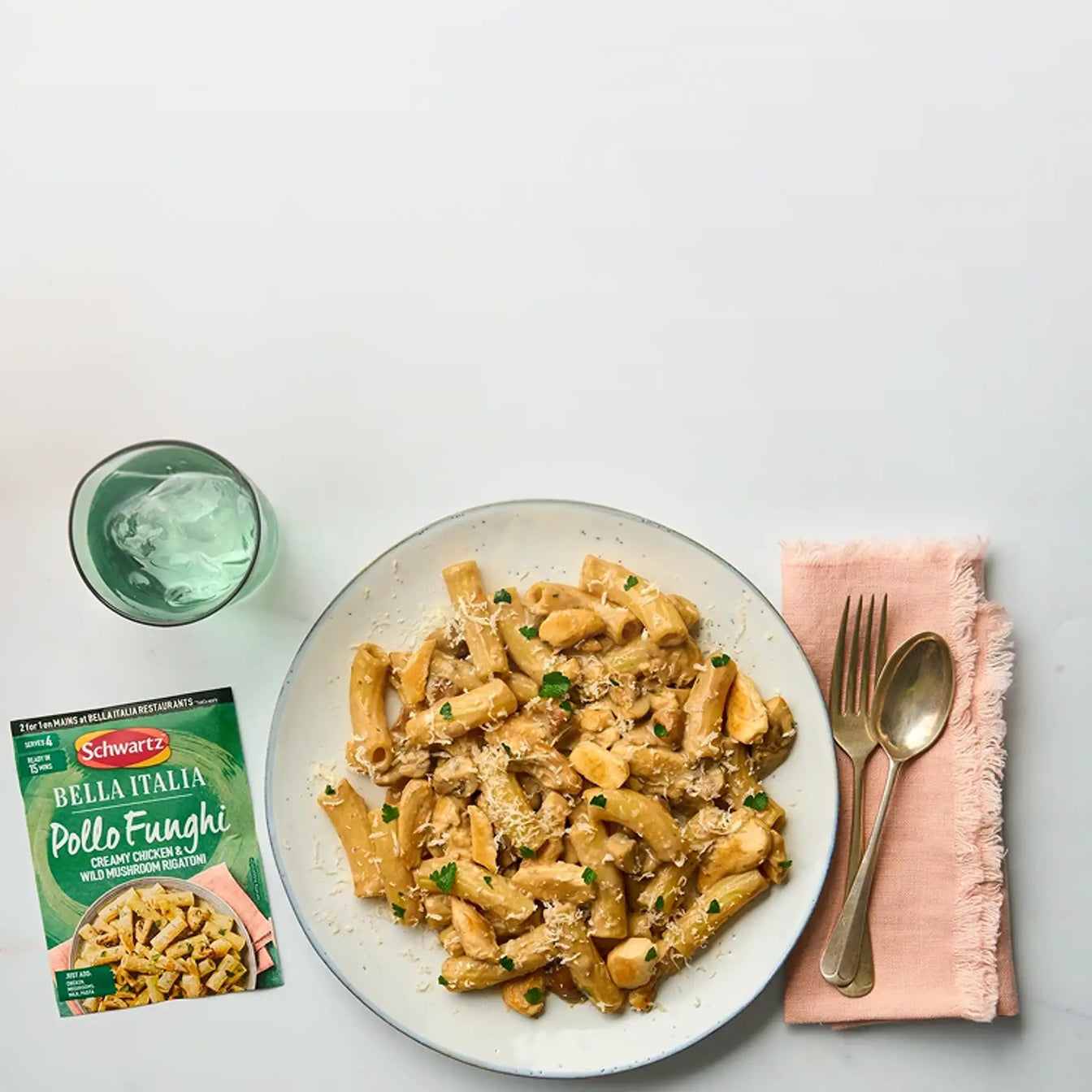 Pasta dish on a white plate with a packet of Bella Italia recipe mix on a gray background