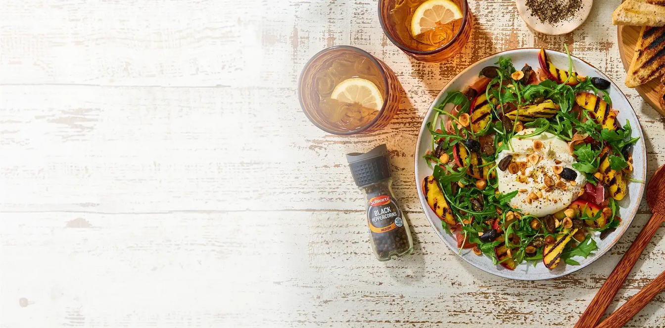 Plated salad with a side of bread and drinks on a rustic wooden table