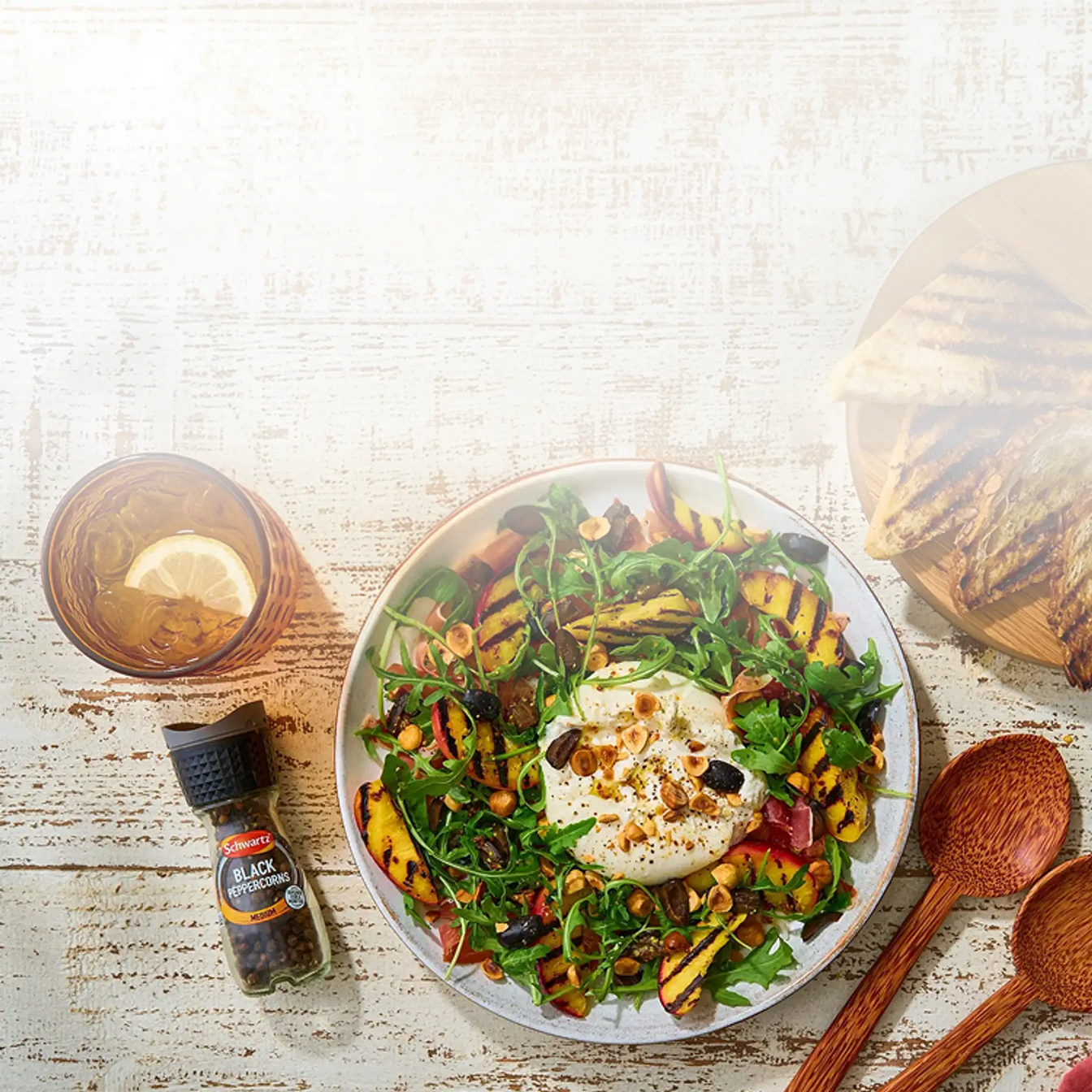 Plated salad with a side of bread and drinks on a rustic wooden table
