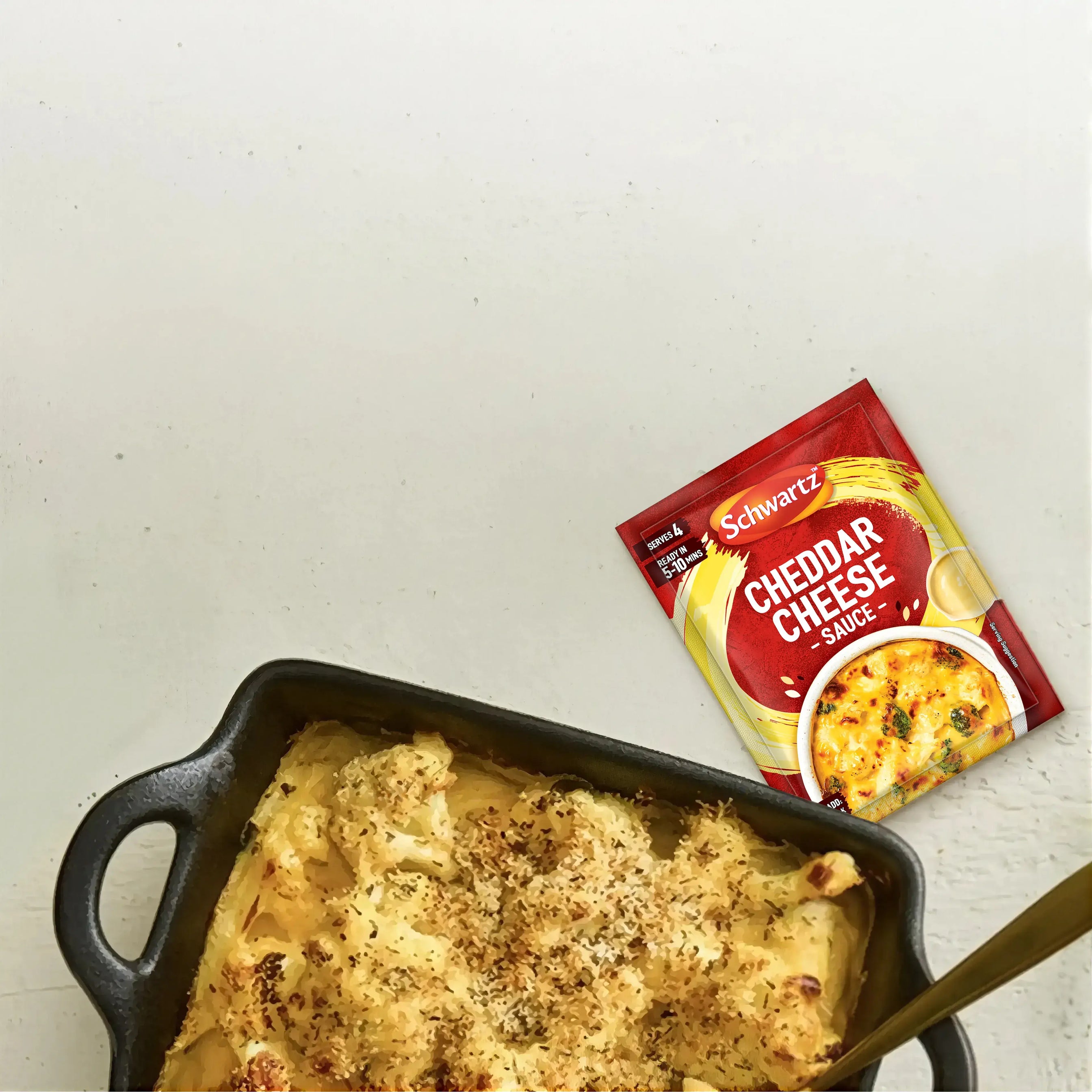 Baked dish with a golden brown topping in a black baking dish on a light gray surface.