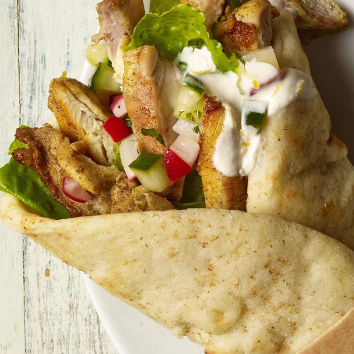 A close-up of a chicken pita wrap filled with seasoned chicken, fresh vegetables, and a creamy sauce, showcasing a delicious recipe idea using the Barrel product.