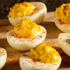A close-up of several delicious Barrel deviled eggs, garnished with paprika and arranged on a wooden board.